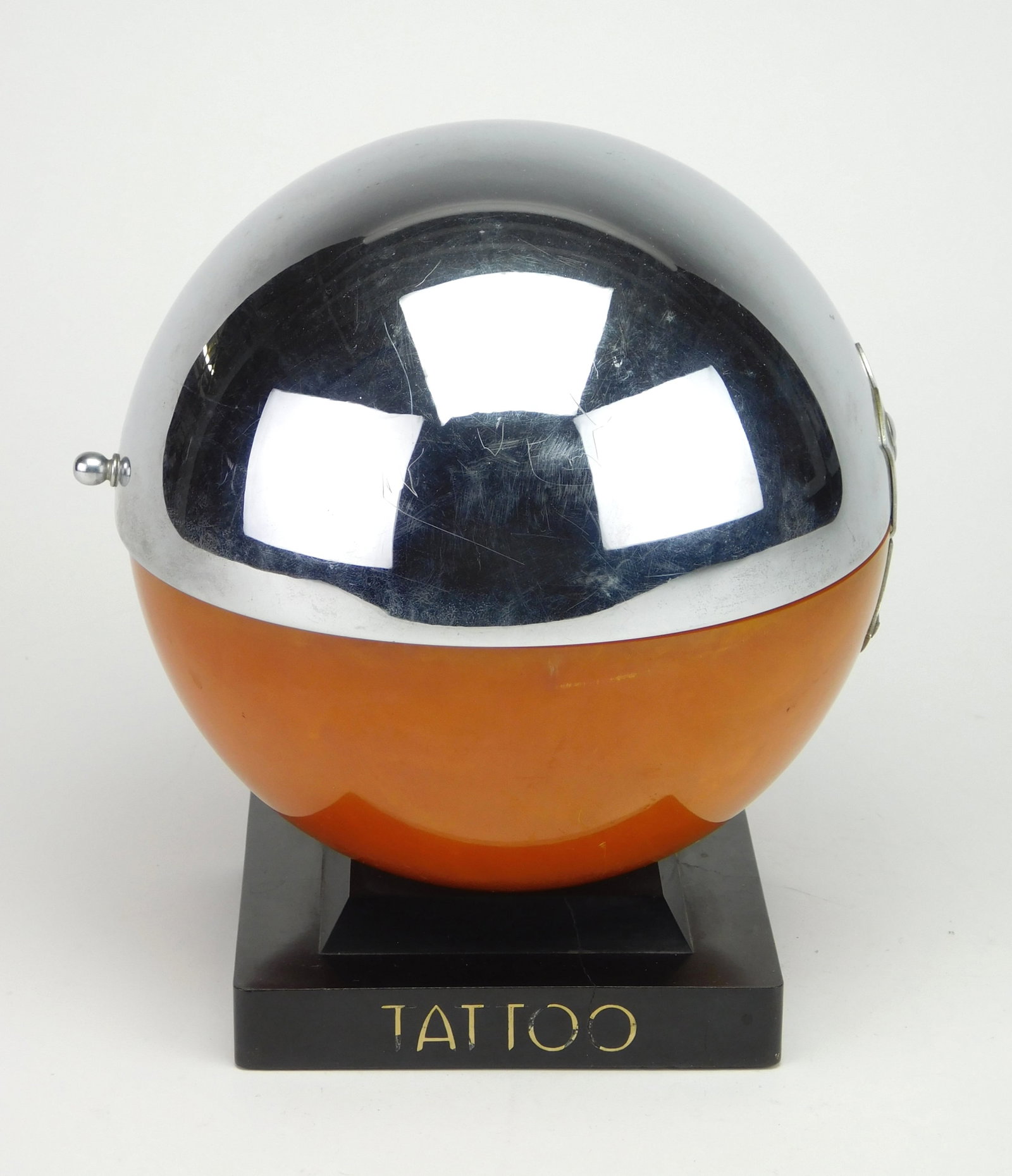 Sphere form counter display box,: top 1/2 sphere is catalin amber with chrome and bakelite square base, 'Tattoo'' on one side. 8'' h Provenance: Private collection- Cleveland, OH