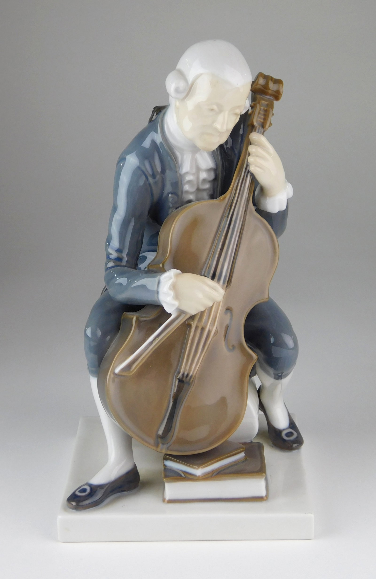 Bing & Grondahl porcelain figurine: depicting a seated male musician playing the cello. Model #2032. Signed and stamped with "B & G" Bing & Grondahl Denmark hallmark on the under side. 8"h Provenance: Privat
