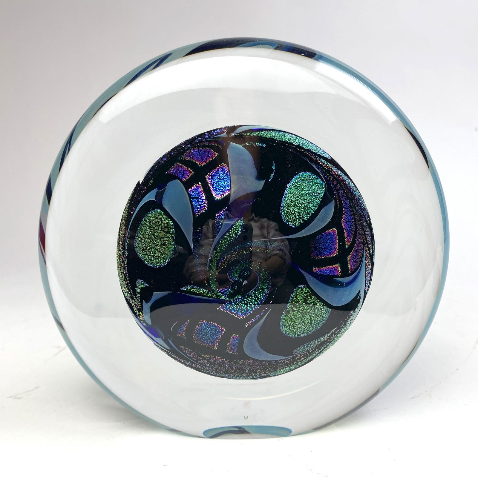 John McDonald Dichroic Iridescent Art Glass Paperweight: The disk shaped paperweight features an abstract dichroic iridescent design encased in clear molten liquid crystal, signed J. McDonald.on underside. 6" dia. 2 1/2"h Provenance: P
