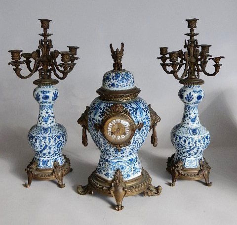 Delft Clock garniture set: 3 Piece 19th c. Delft Clock Garniture, porcelain with bronze mounts, comprising a clock and a pair of five light candelabra having blue on white decoration, lion head handles, winged Griffin finial. 2