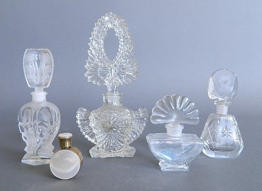 5 Glass perfume bottles: 4 Clear glass perfume bottles with stoppers; along with a small glass perfume bottle, covered in brass and decorated with mother of pearl; minor chipping on caps of stoppers, otherwise good condition,