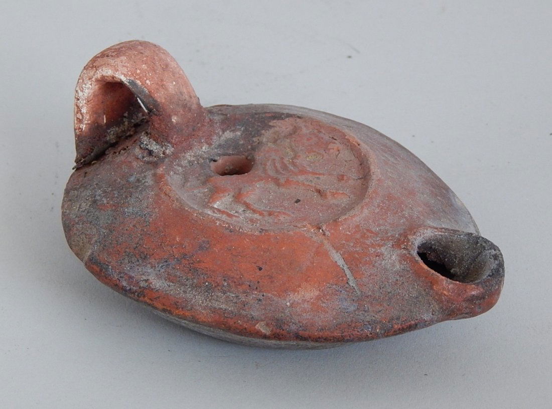 Roman red earthenware oil lamp: Roman red earthenware oil lamp, central medallion has an image of a walking lion. 1 7/8''h, 4 1/2'' across