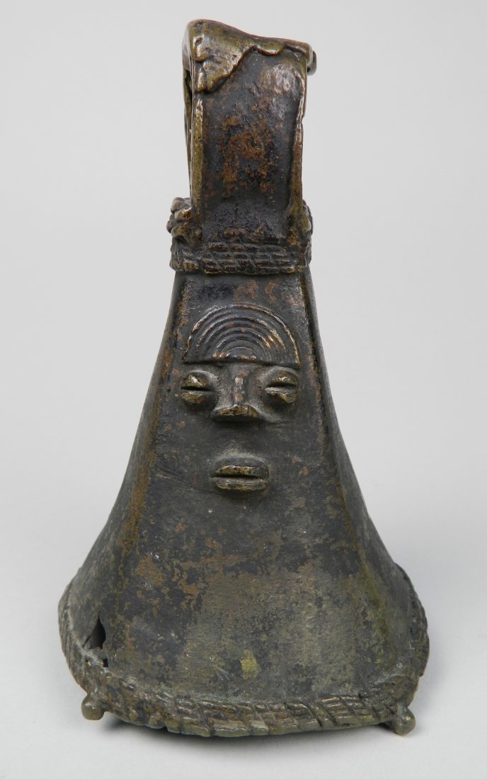 Mid 20th c. Iron bell, Yoruba: Mid 20th c. Iron bell of squared conical form with face, Yoruba, 2'' crack near top of the body (opposite of face). 4 1/4'' dia., 6 3/4''h