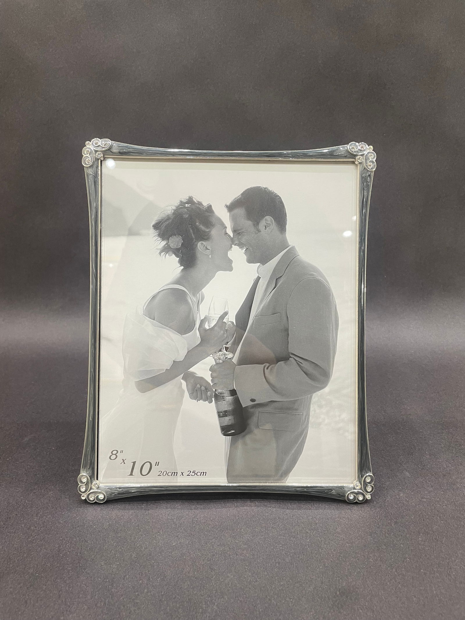 Grey 8x10 Photo Frame with Stones: 8x10 Grey Frame with Stones Gracefully contoured silver-tone frame accented with decorative scrollwork and sparkling stone details at each corner. Designed to hold an 8" - 10" photograph, this timele