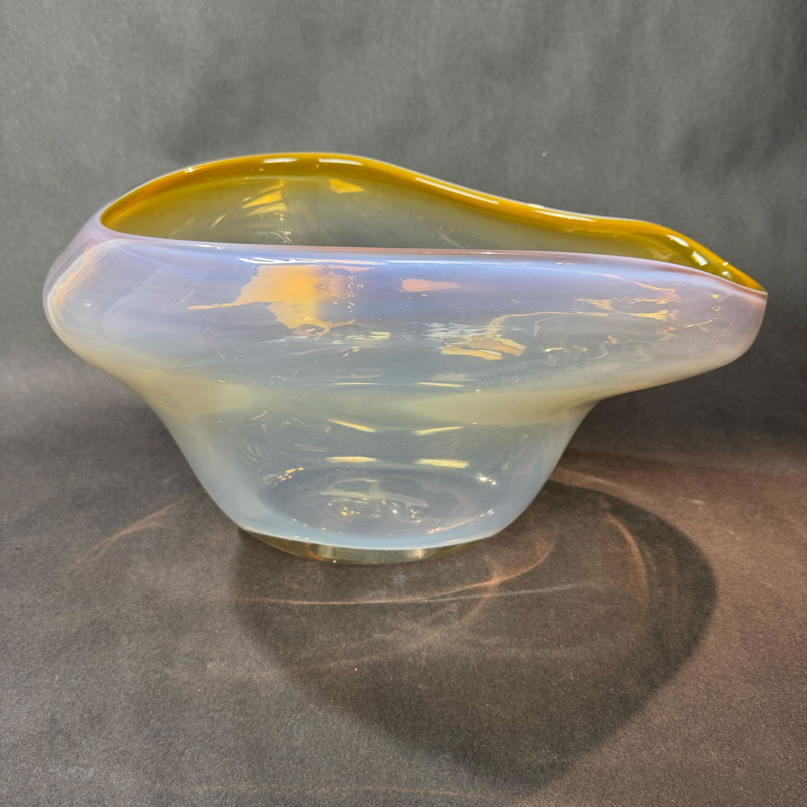 Kavana 8.5 H x 16 W Glass Bowl: Artist: Kavana Title: Huxley Bowl (Amber) Medium: Glass Size: 8.5 H x 16 W x 10 D Weight: 13 lbs. This elegant glass bowl features a softly undulating form with a translucent body that shifts from mi