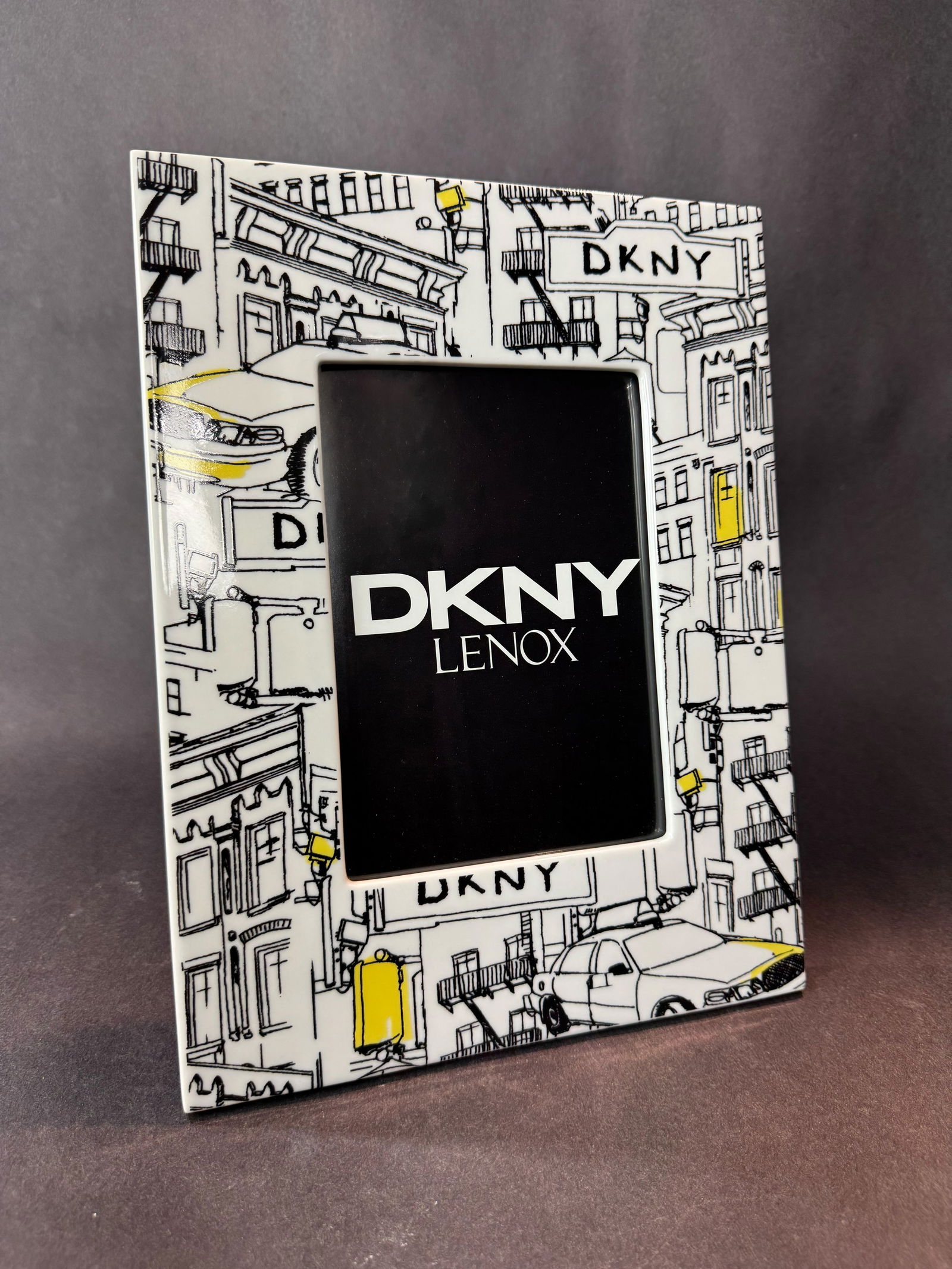 Lenox 11.5 H x 8.75 W Ceramic Photo Frame: Artist: Lenox Title: DKNY Taxi Frame Medium: Ceramic Photo Frame Size: 11.5H x 8.75 W x 0.5 D Weight: 2.75 lbs. This stylish DKNY Lenox frame features a playful, illustrated cityscape inspired by the
