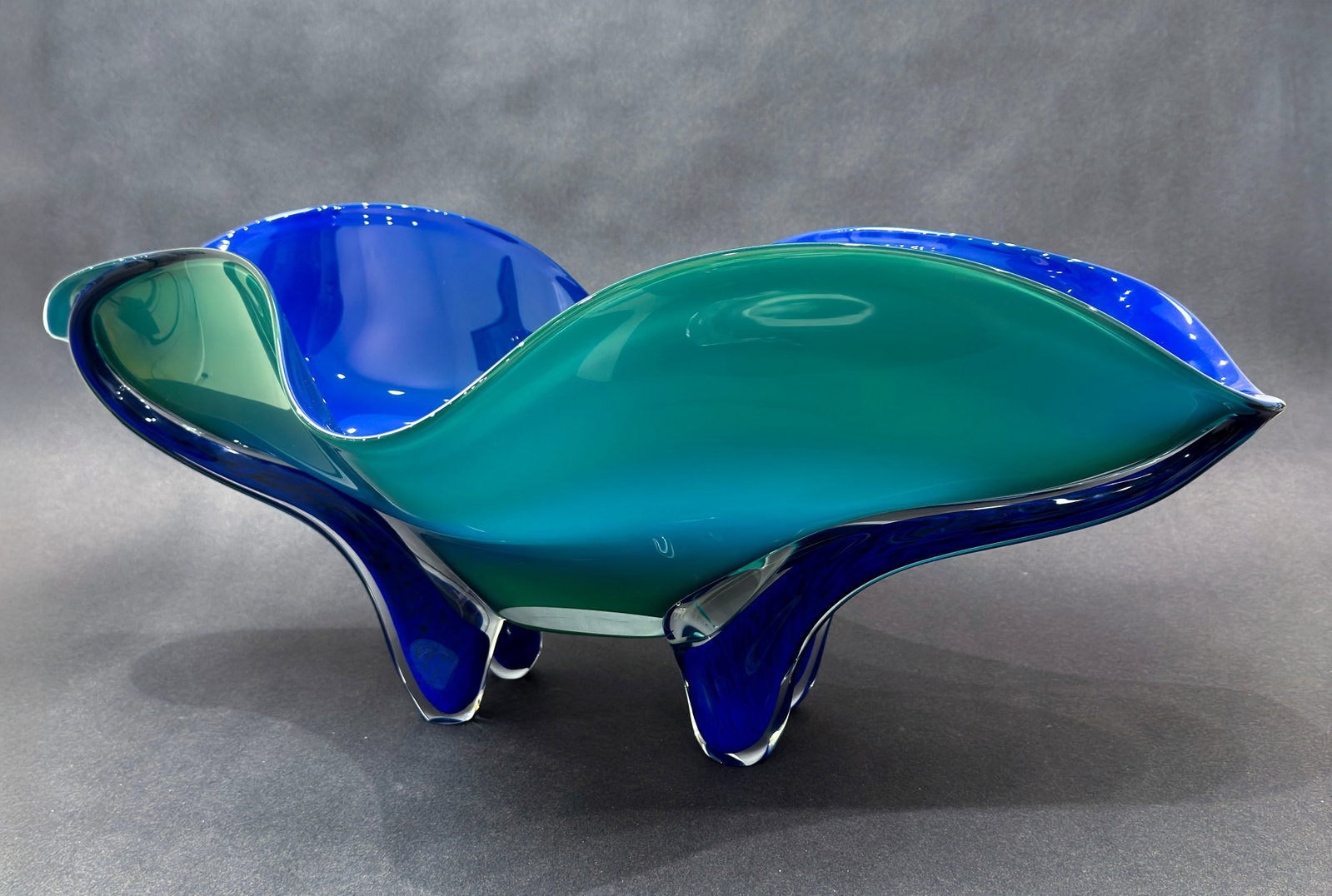 Ed Branson 15.5” H x 23.5“ W x 9.5” D Blue Tropical Bowl: Artist: Ed Branson Title: Tropical Bowl in Caribbean Blue Medium: Glass Size: 15.5” H x 23.5“ W x 9.5” D Weight: 12.5 lbs. Edition: Original This elegant hand-blown glass bowl features f