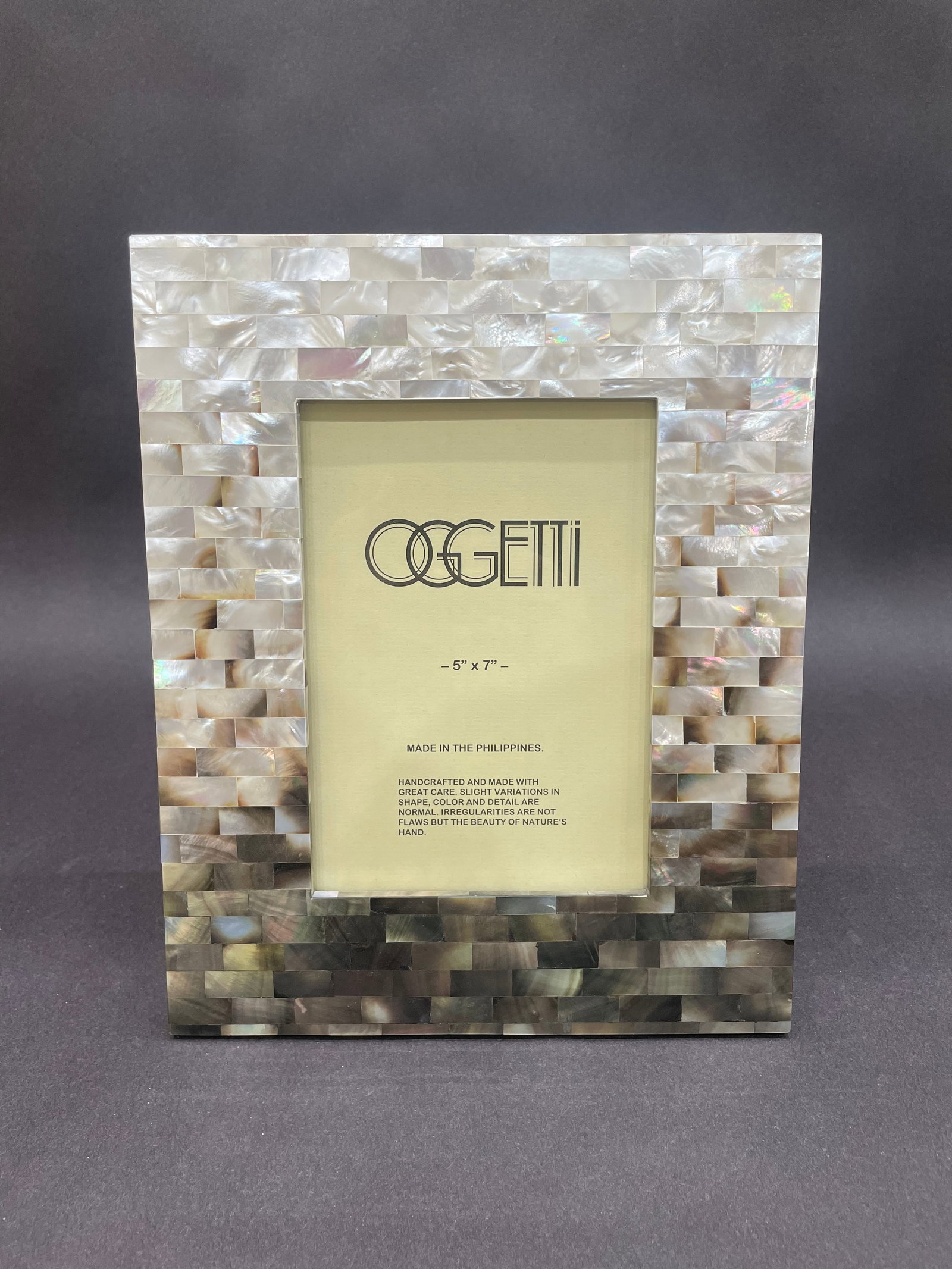 Oggetti Studios 10.5" H x 8.5" W Photo Frame: Artist: Oggetti Studios Title: 5x7 Shell Tile Frame Medium: Glass Size: 10.5" H x 8.5" W x 0.5" D Weight: 1 lbs. Edition: Open This refined picture frame is crafted from hand-set tiles of luminou