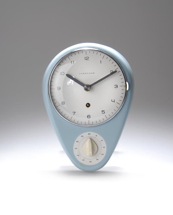 Max Bill, Küchenuhr, 1956: Gehäuse in Ei-Form, Zifferblatt mit scharnierter Glastür, Sekundenuhr mit Drehschalter. Batteriebetrieben. 25 x 18 cm. Ausführung: Junghans AG, Schramberg. Steingut, hellblau gespritzt, glasiert; Z