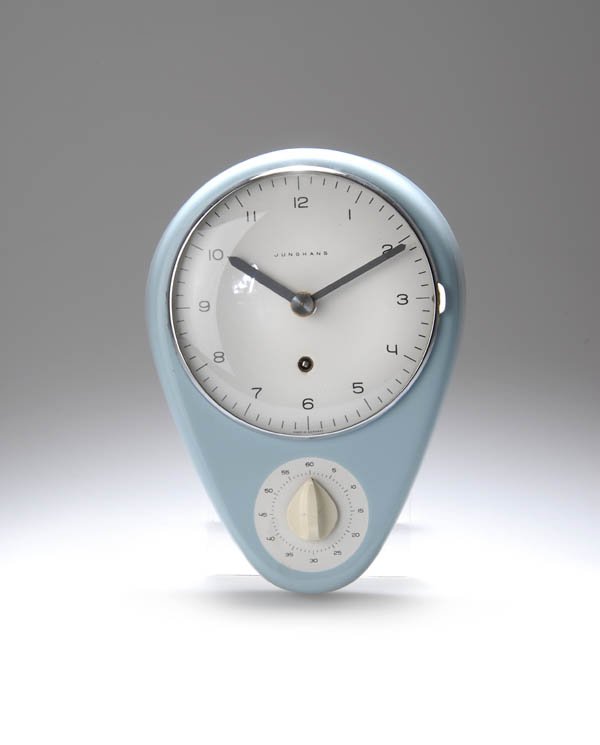 Max Bill, Küchenuhr, 1956: Gehäuse in Ei-Form, Zifferblatt mit scharnierter Glastür, Sekundenuhr mit Drehschalter. Batteriebetrieben. 25 x 18 cm. Ausführung: Junghans AG, Schramberg. Steingut, hellblau gespritzt, glasiert; Z