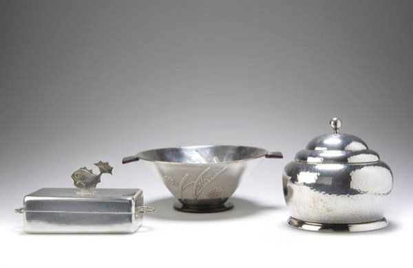 544: Wellner Söhne, August, Aue; Sardinendose, um 1930: Rechteckige Form, die Kanten abgerundet, Schmalseiten mit fünffach gebogten Griffen, flache Deckelhaube mit stilisiertem Flachfisch als Handhabe. H. 10 cm; 8,5 x 20 cm. Nickelsilber, versilbert, Eins