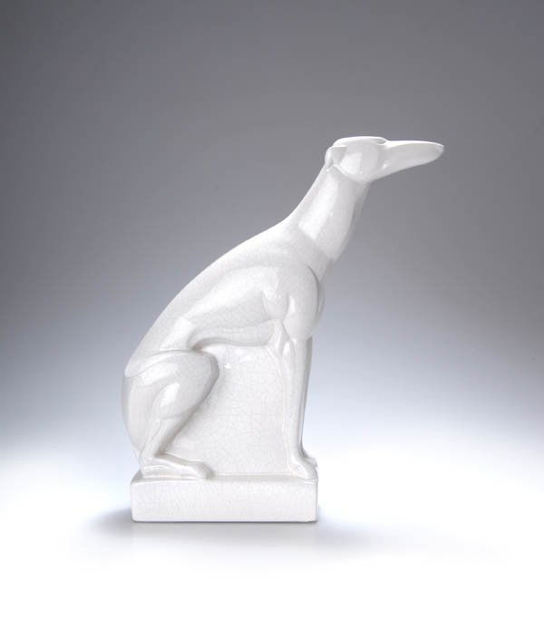 Charles Lemanceau, Sitzender Windhund, um 1925: Stilisierter Windhund, den Kopf nach vorn gestreckt, auf blockhaftem Stand über rechteckigem Hohlstand. H. 29 cm. Ausführung: Fayencerie Saint Clément, Saint-Clément. Weißer Steingutscherben, gla