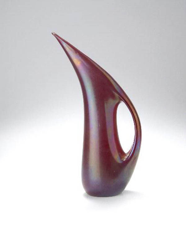 Giorgio Ferro, Kanne 'ansa volante', 1952: Amorphe, abgeflachte Gefäßform über ovalem Stand, aus der Form gezogener Henkel, Mündungsrand einseitig spitz hochgezogen. H. 32, 9 cm. Ausführung: Arte Vetreria Muranese (A.Ve.M.). Dunkelrot get