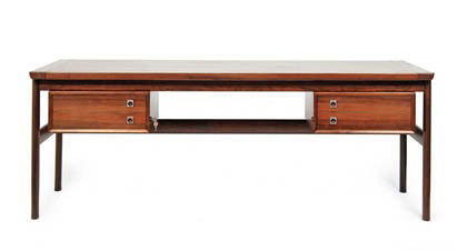 Arne Vodder, Schreibtisch, um 1965: Beine auf ovalem Stand, ausgesparter Fußraum flankiert von je zwei Schüben, auskragende Platte. Ausführung: Sibast Furniture Co., Dänemark. Palisander, furniert, Zuggriffe aus Weißmetall, ringfö
