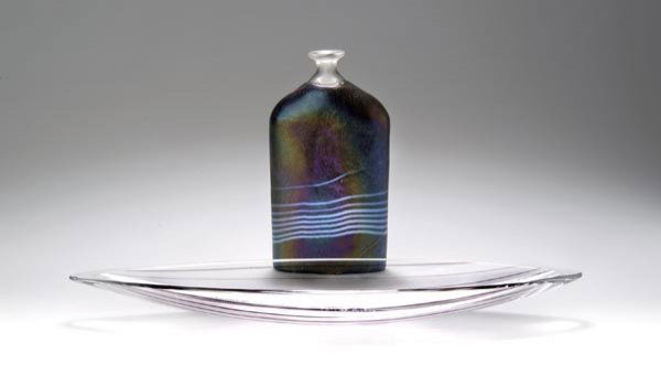 Bertil Vallien, Flaschenvase, um 1990: Über querovalem Stand gerade, zweiseitig abgeflachte Wandung, schräg eingewölbte Schulter, enger Hals mit ausgestellter Mündung. H. 17,2 cm. Ausführung: Kosta Boda, Glasbruk, Schweden. Farbloses