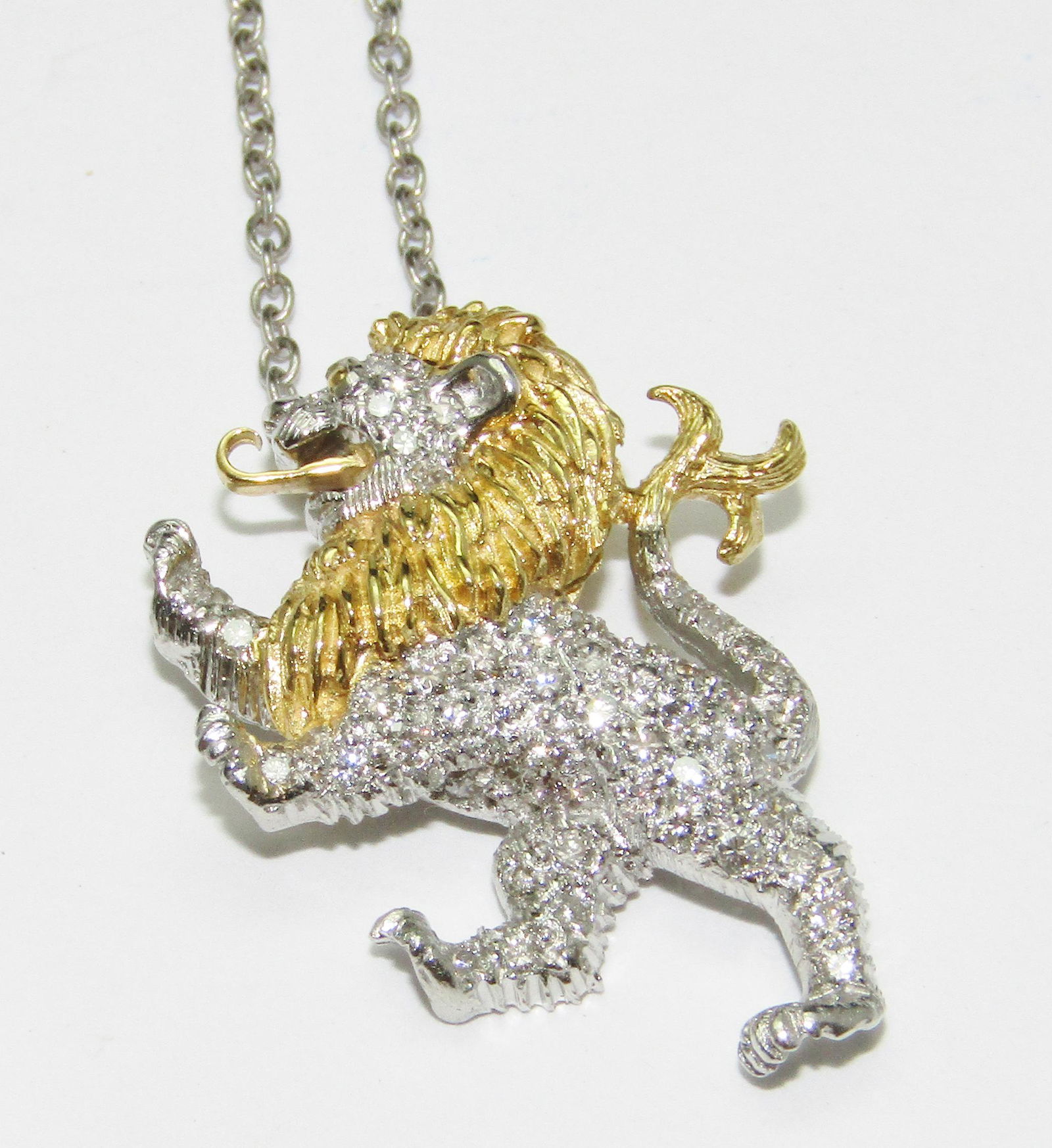 Schuler McTeigue Platinum and 18Kt Gold Lion Pendant: Lion pendant in Platinum and 18 karat yellow gold with 57 round full cut and single cut diamonds at 0.28 carat total weight, G-H color/VS-1 to VS-2 clarity. White gold neckchain. Trademark: Schuler Mc