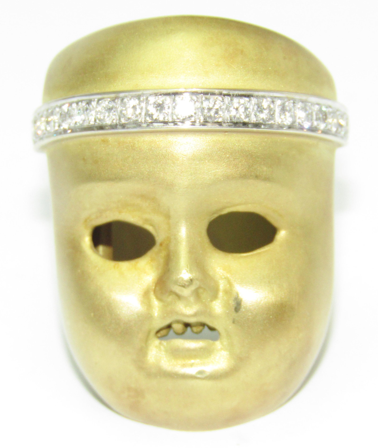 Kieselstein Cord 18Kt Gold Ring: 18 karat yellow gold ring with a face or mask with teeth in the mouth. Diamond set head band. 37.6 grams. Marked: Kieselstein Cord. Appraised Fair Market Value (FMV) is $3000. Ring size 6.5