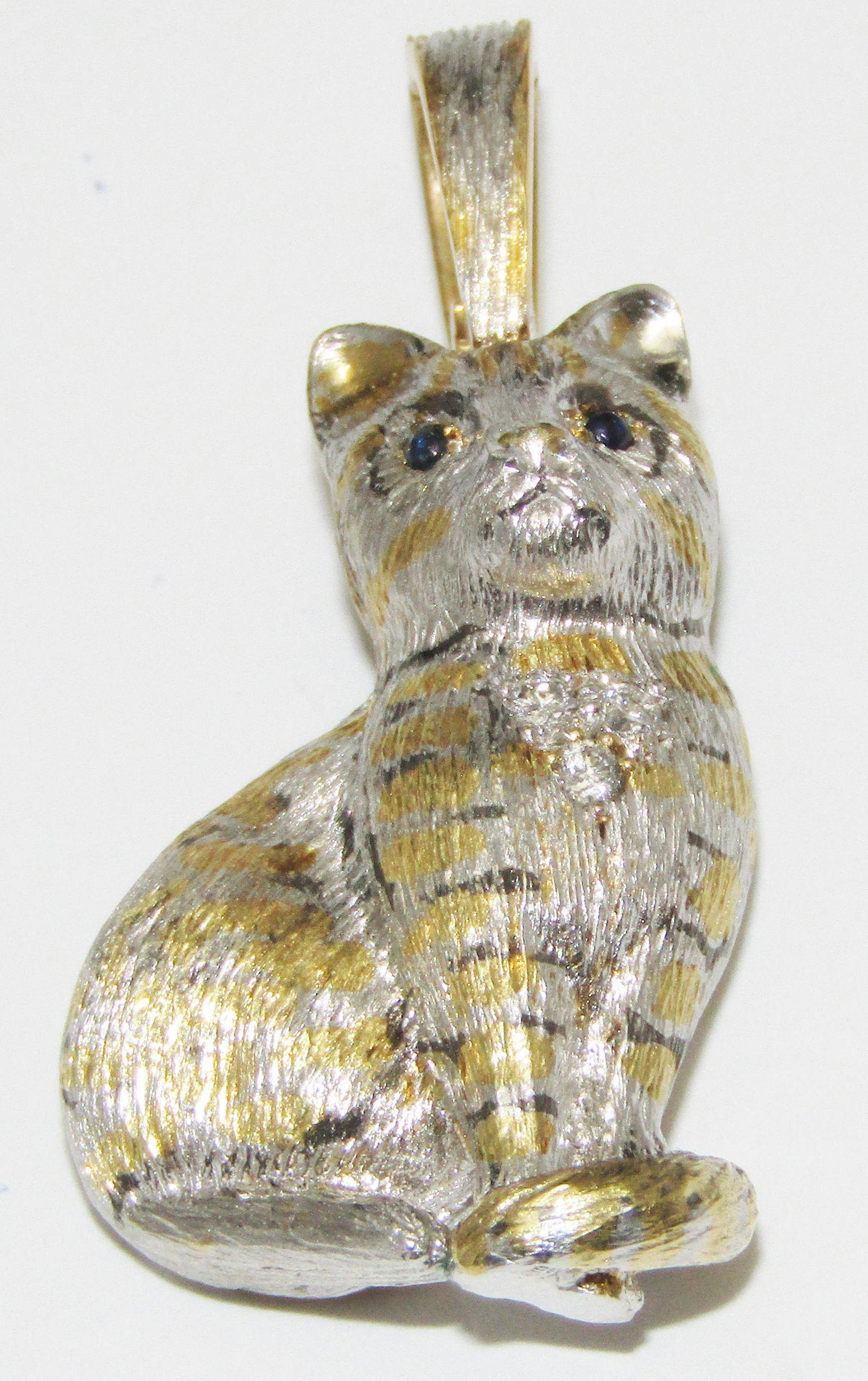 18Kt White Gold and Enamel Cat Pendant with Sapphires and Diamonds: 18 karat white gold (has yellow gold embellishments) Cat pendant with cabochon sapphire eyes. Diamond melee in the chest. Black enamel accents. 16.6 grams. Appraised Fair Market Value (FMV) is $750.