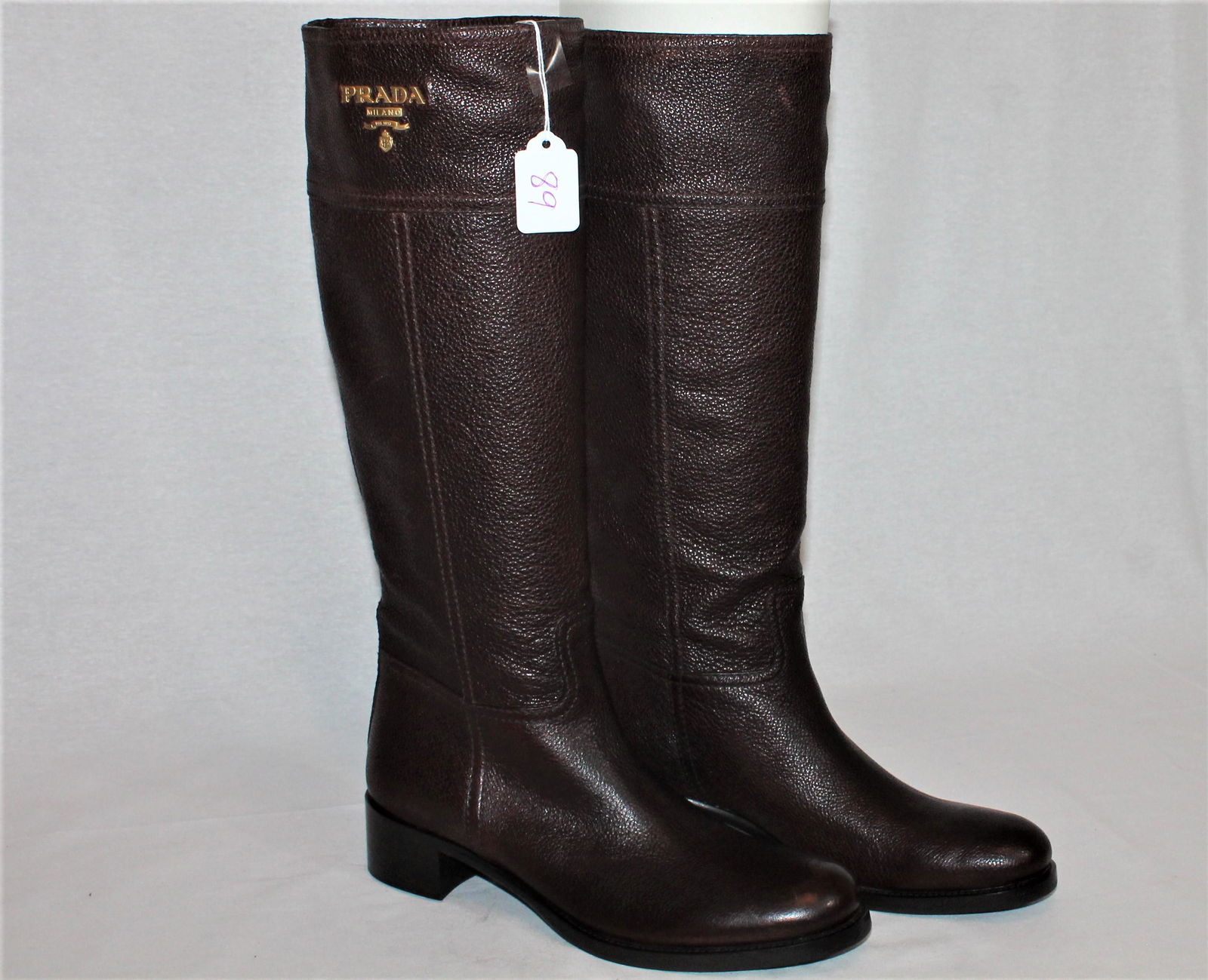 Prada knee length brown boots: Sophisticated Prada knee length brown boots with gold tone logo detail on the sides. Never worn, size 37, original box.