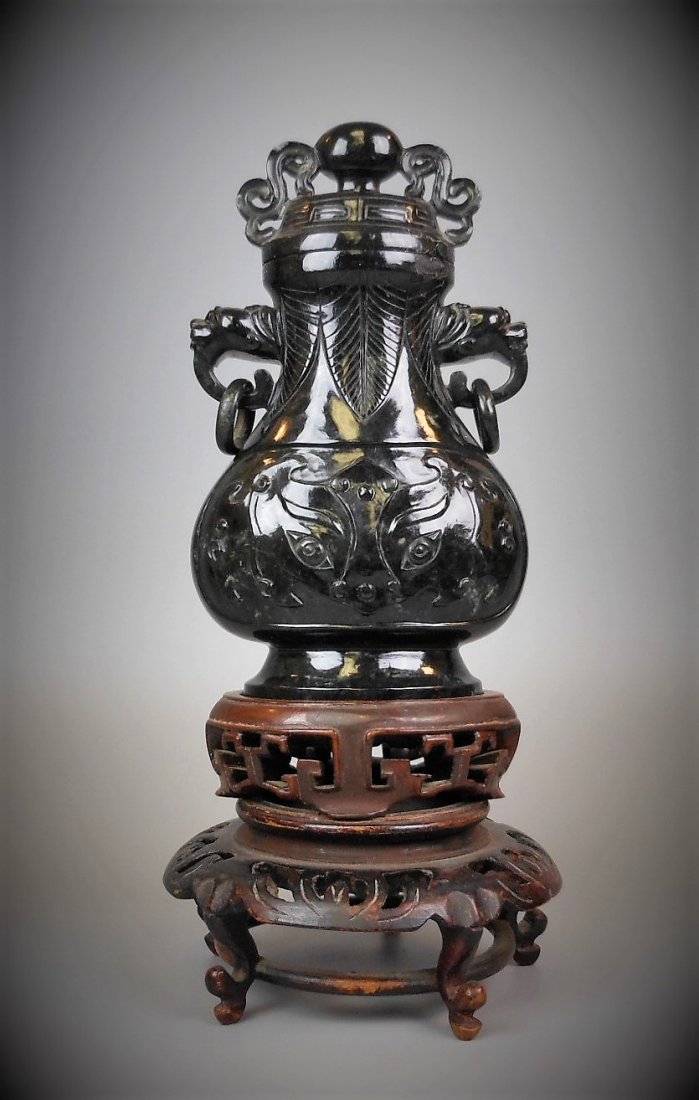 A CHINESE HETIAN SPINACH-GREEN JADE VASE WITH STAND: A CHINESE HETIAN SPINACH-GREEN JADE CARVED VASE WITH TWO RING HANDIES WITH LOOPED RINGS WITH STAND H: 6.3 in (16 cm) Weight: 626 g Provenance: property from a private San Francisco collector 和&