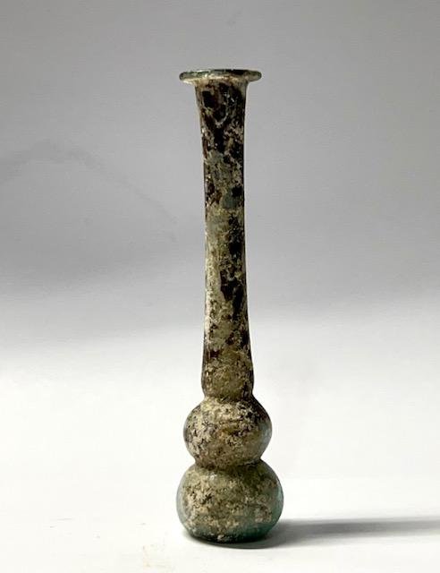 Ancient Roman glass unguentarium with two-part body: Roman glass unguentarium with two-part body, 2nd - 3rd Century BC, the base nearly flat, the neck long and tubular, the mouth flattened with rim folded. intact . Size: 10.5 cm x 2.5 cm Ex private Long