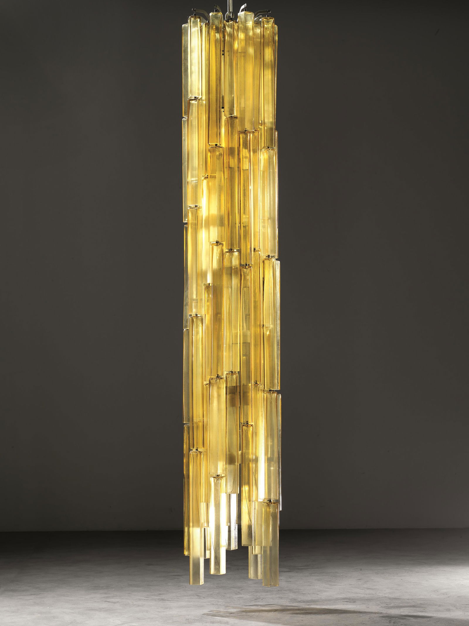 Vinicio Vianello (Venezia, 1923 - Zelarino, 1999): Vinicio Vianello (Venezia, 1923 - Zelarino, 1999) LAMPADARIO struttura in metallo con pendenti in vetro soffiato nei toni dell’ambra Produzione Salviati & C., Venezia, 1960 circa cm 40x250 S