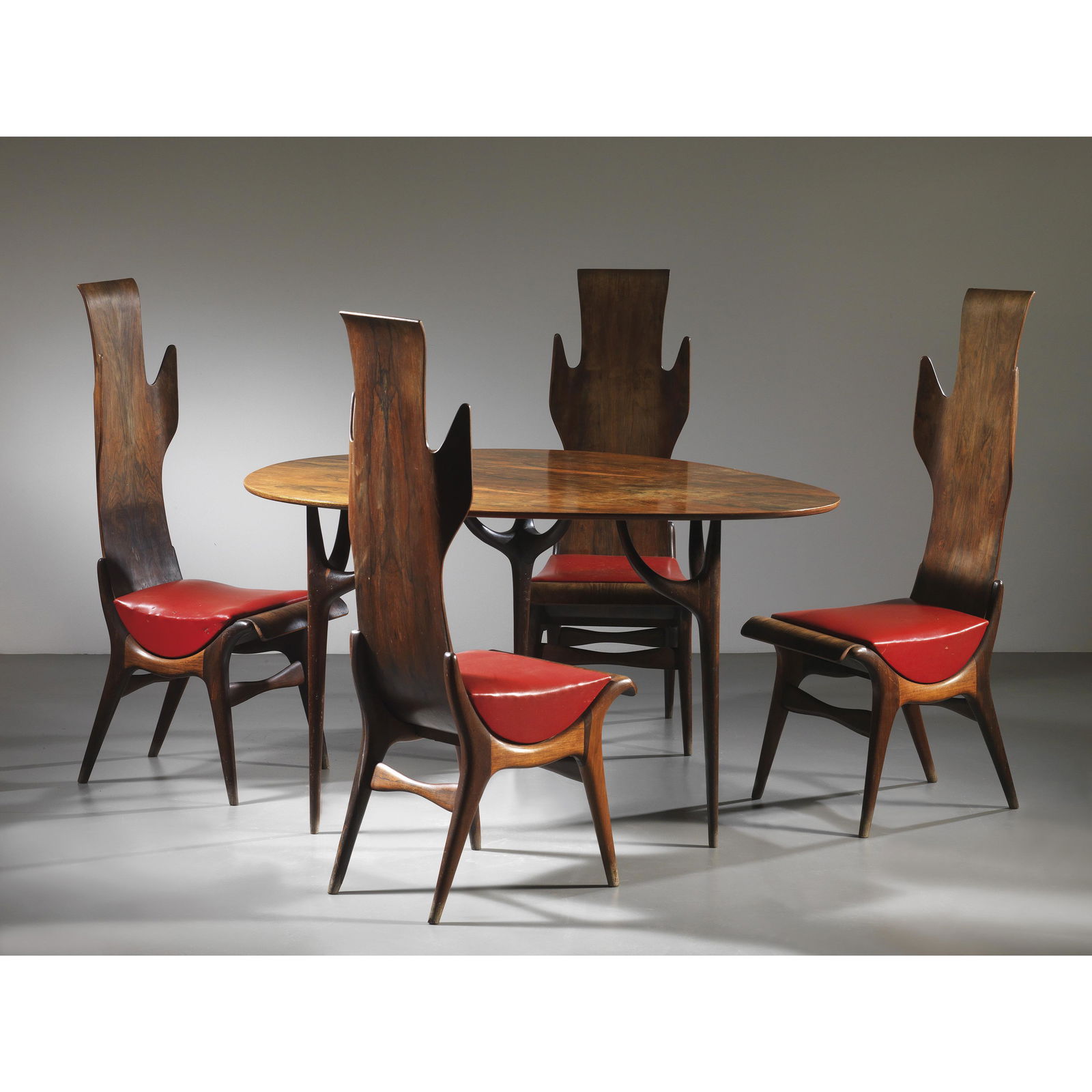 Dante Latorre (XX sec.) FOUR CHAIRS AND A TABLE: WOODEN STRUCTURE AND RED LEATHER QUATTRO SEDIE E UN TAVOLO in legno e cuoio nei toni del rosso Produzione Pozzi e Verga, Italia, 1955 circa sedie cm H116x42x57 tavolo 75x138x109 Bibliografia di confro