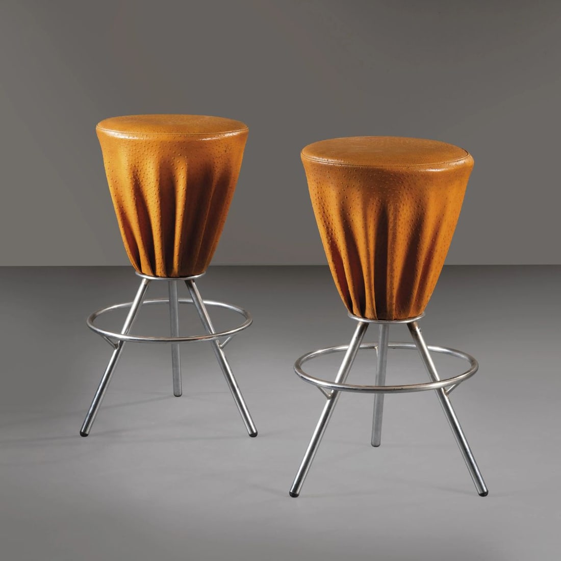 COPPIA DI SGABELLI: A COUPLE OF STOOLS COPPIA DI SGABELLI struttura in metallo e cuoio nei toni dell'arancio Produzione Italia, 1990 circa alt. cm 83 e diam. cm 50 