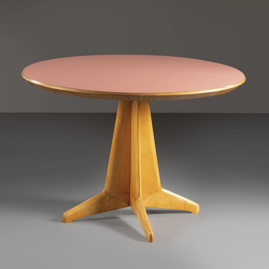 A WOODEN TABLE: A WOODEN TABLE UN TAVOLO in legno, ripiano in legno laminato nei toni del rosa Produzione Italia, 1950 circa alt. cm 80 e diam. cm 120
