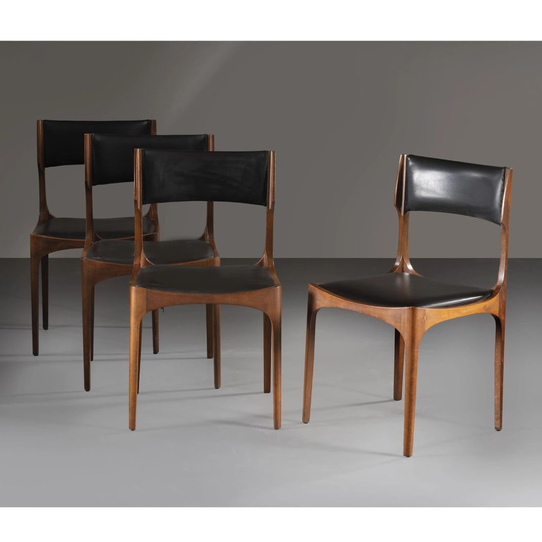 Giuseppe Gibelli: Giuseppe Gibelli (Sec. XX) FOUR «ELISABETTA» CHAIRS QUATTRO SEDIE MODELLO ELISABETTA in legno, seduta rivestita in pelle nei toni del nero Produzione Sormani , Italia, 1960 circa cm H83xL47xP45