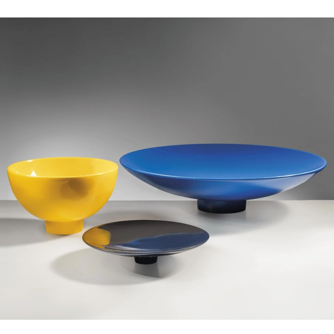 Alessandro Mendini: Alessandro Mendini (1931 - 2019) TRE CIOTOLE DELLA SERIE CUCULIA in resina nei toni del giallo, del nero e del blu Produzione Zanotta , Italia, 1985 ciotola gialla diam. cm 25 e alt. cm 15 piatt