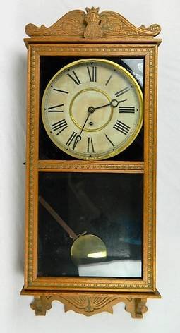 Hamburg American Clock Co. Pendulum Wall Clock: Large dark wood working wall clock, with decorative 3 panel bevelled glass. Key is included. Approximate Measurements: 30" L x 14" W, Face 7".