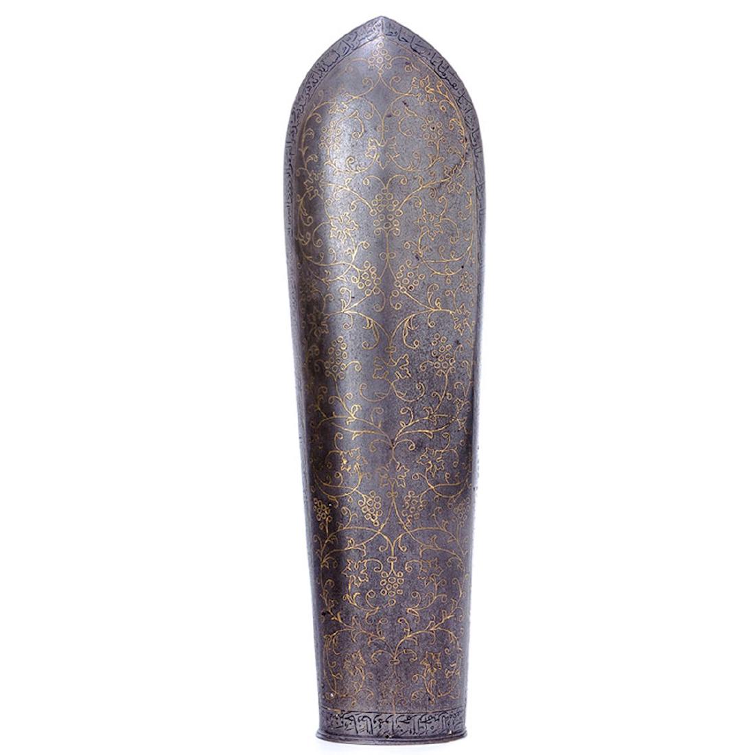 ARMGUARD BAZU BAND W/GOLD INLAY, PERSIA: Armguard of Damascus steel covered with a viney gold inlay work and etched inscriptions in Arabic script around. length 13 1/4 in., width 3 3/4 in.