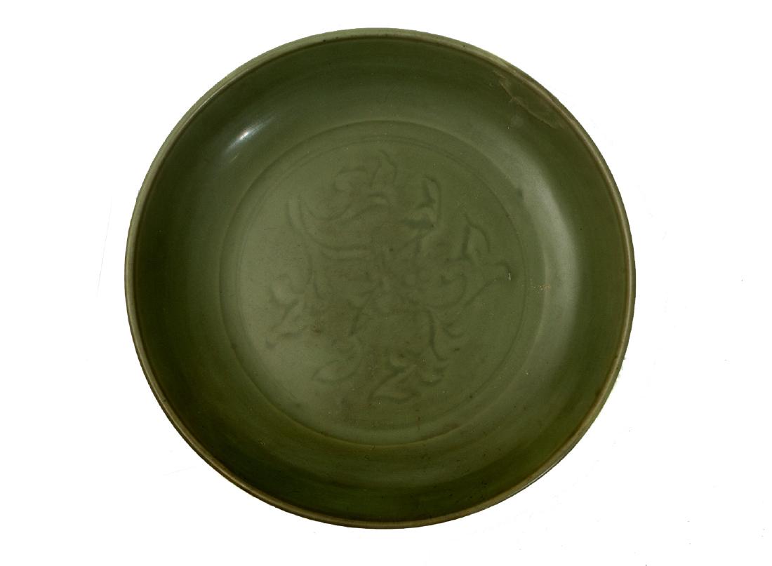 LARGE CELADON PLATE, CA. XV-XVI CC.: Curved in the center with olive green tone floral motif evenly spread over the base. On the base there is an unglazed circle. 15th cen, Ming Dynasty. A similar example may be found at Christie's sale