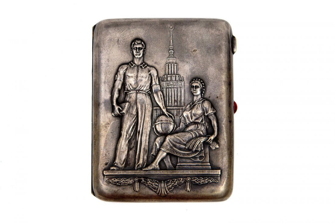 EARLY SOVIET CIGARETTE CASE WITH JEWELED LOCK: German silver early Soviet cigarette case with repousse design of Moscow State University and two figures of a standing make student with study book and seated figure of a female student with a globe.