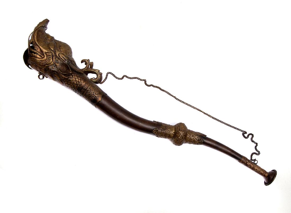 MALAYSIAN BRASS DRAGON HORN, 19TH C.: Nicely hammered buddhist ritual Tibetan Makara sea dragon trumpet or horn with chain. Ca. 1900. Dimensions: Length: 20 in. (51 cm.)