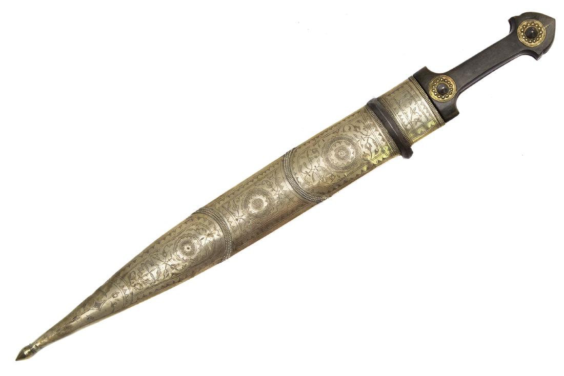 LARGE DAGESTAN BRASS MOUNTED DAGGER KAMA, 19TH C.: Horn grip scales with two brass and silver rivets, double edged blade, wooden brass-mounted scabbard, with one steel fitting, the back of the scabbard is covered with original leather. The floral desi