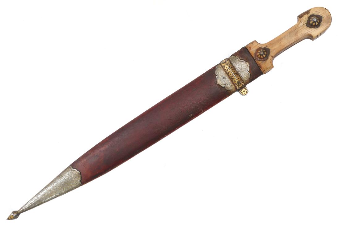 CAUCASIAN KINDJAL DAGGER WITH CHISELED BLADE: Carved hilt with two gold inlaid rosettes, blade decorated with chiseled lion and vines on ricasso, wooden scabbard covered with original burgundy leather, steel mounts decorated with chiseling and go