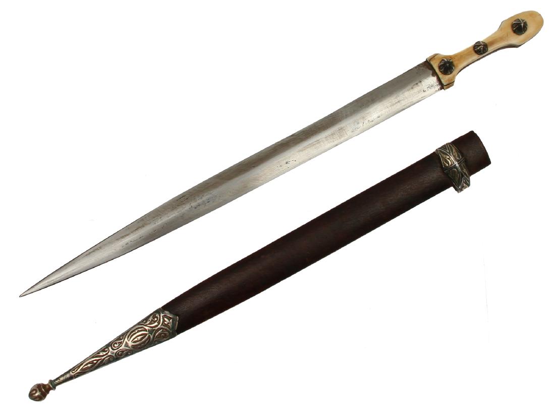 CAUCASIAN ISLAMIC SILVER MOUNTED KINDJAL DAGGER: Carved black and white grip scales retained by three silver pins decorated with engraving, double edged diamond-cut shaped blade, wooden leather-covered scabbard with engraved silver mounts. 19th cent