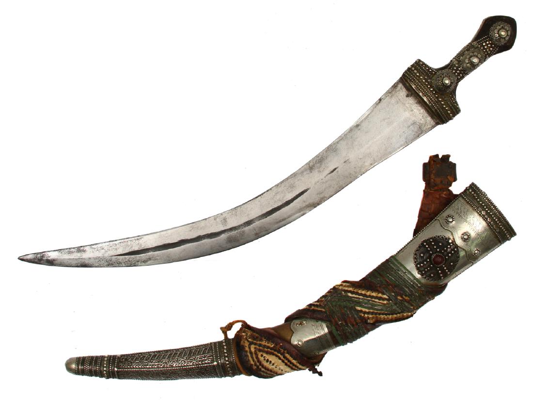 LARGE SAUDI ARABIA WAHABITE JAMBIYA, 19TH C.: Hilt and scabbard fittings are richly decorated with silver bands, rosettes, and chiseling, scabbard is covered with leather and wrapped with multi color leather belt , the blade has one fuller in the