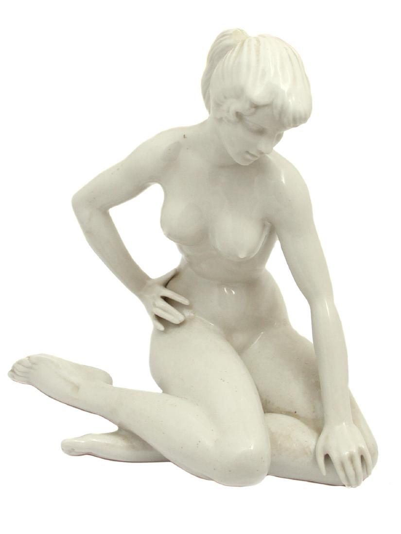 A DRESDEN GLAZE PORCELAIN FEMALE NUDE FIGURINE: A Dresden white plaster porcelain figurine of a seated nude girl. Blue glaze stamped on the base under glaze "Original Germany", "D". Dimensions: H: 8 in., (20 cm.)