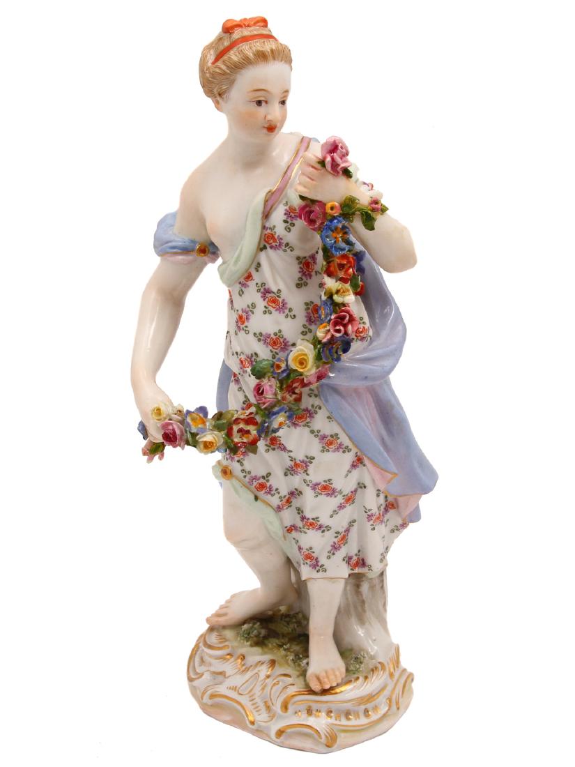 A MEISSEN PORCELAIN FIGURINE WITH FLOWER GARLAND: A hand painted Meissen porcelain figurine depicting a classical maiden holding flower garland. Featuring under glaze blue crossed swords mark and impressed impressed G 84, 65. Dimensions: H: 8 in., (2