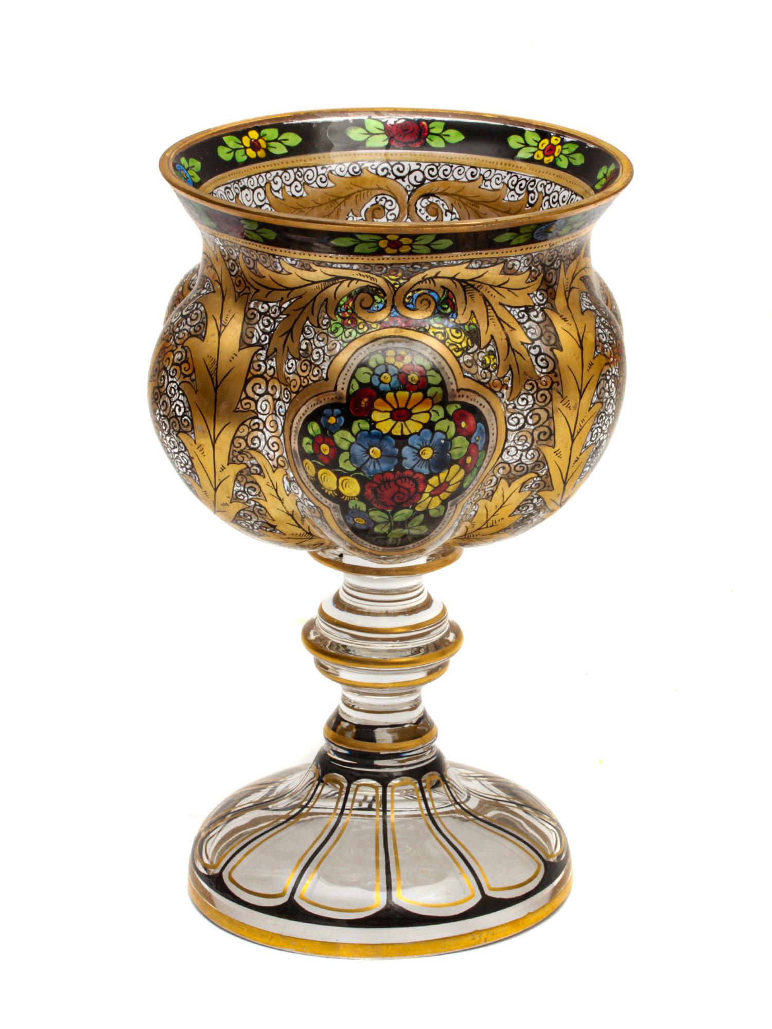AN ANTIQUE ART GLASS CHALICE BY MOSER LATE 19TH C: A delightful glass chalice skillfully hand-blown, painted, and inlaid in Bohemia (Czech Republic). Decorated with delicate ornaments and large golden leaves framing two cartouches with a bouquet of fl