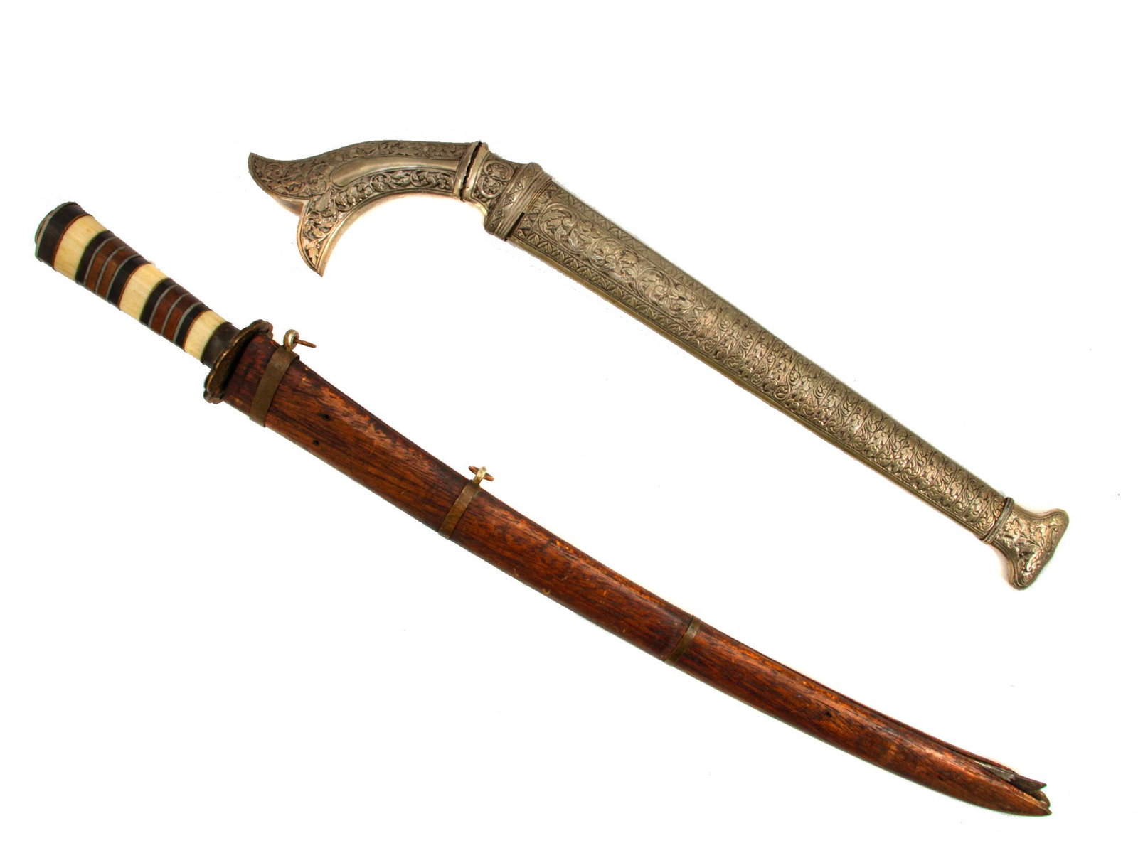 A MALAYSIAN SHORTSWORD (PARANG) AND SEKIN DAGGER: A parang with a nice low-grade silver embossed scabbard and pommel, double-edged blade s slightly pitted. A sekin dagger in a wooden sheath with a single-edged blade decorated with engraving along the