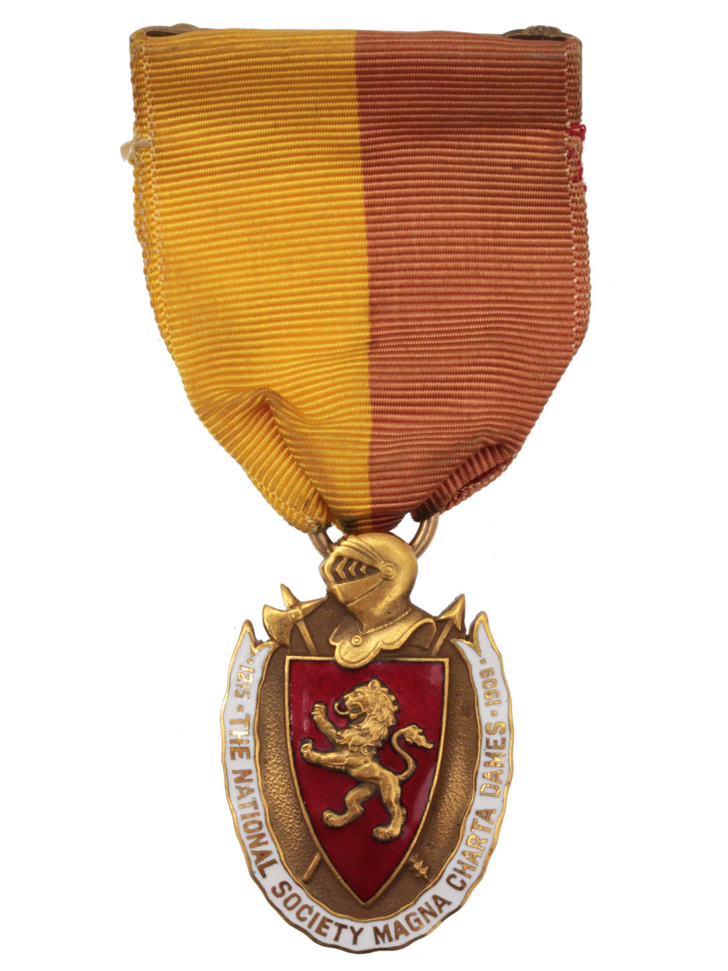 A MAGNA CHARTA DAMES MEMBERSHIP 14K GOLD BADGE: Of an oval form with a knightâ€™s helmet and ax at the top, the obverse features a red enameled shield with a superimposed lion, the edge bordered by a white enameled banner inscribed 1215 THE NA