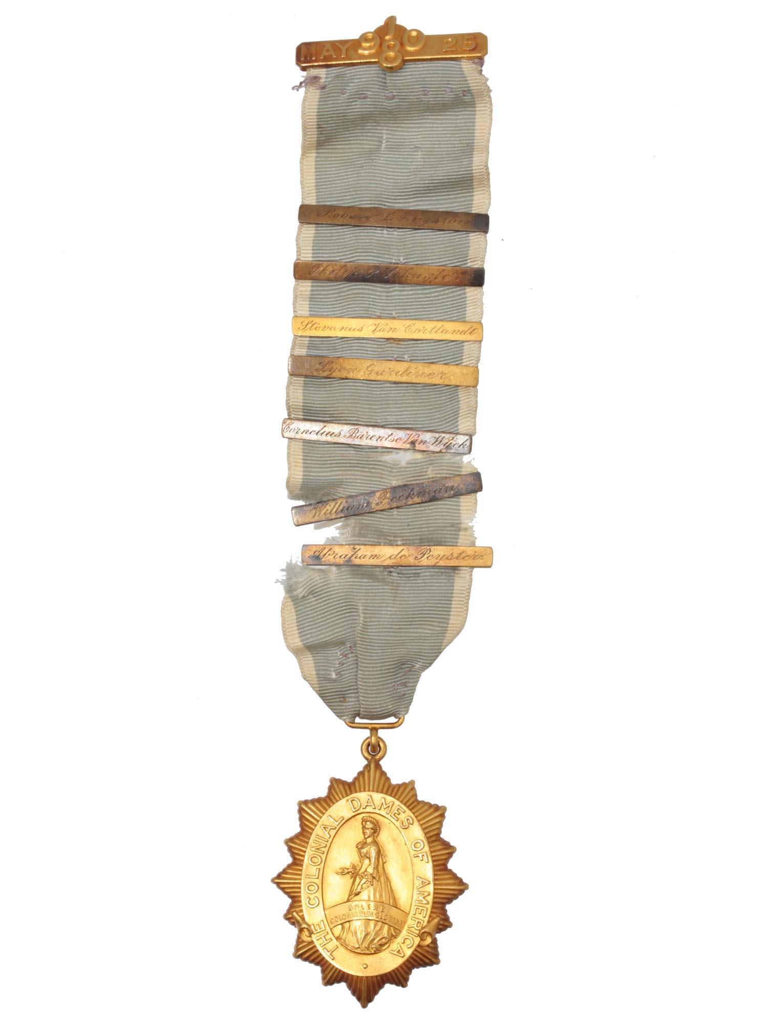 A 14k GOLD COLONIAL DAMES OF AMERICA MEDAL: A 14k gold The Colonial Dames of America Medal. The back of the medal is marked with S/N 29 and is awarded to Gertrude Van Cortlandt Hamilton on May 25, 1980. The ribbon holds various names. The medal