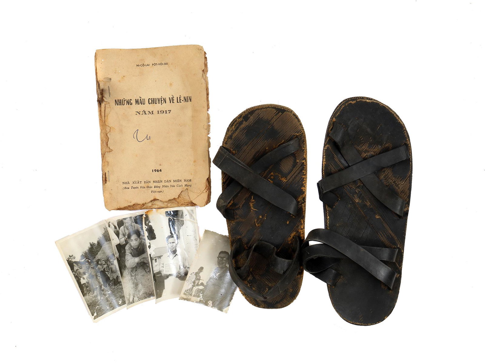A LOT OF 2 VIETNAMESE SANDALS, PHOTOS AND BOOK BY NICOLAY POTVOISKI: A lot consisting of 2 leather and rubber sandals, 4 photos with descriptions and dates on the back in English and Vietnamese, and a large portion of the book "Stories about Lenin" by Nicolay Potvoyski