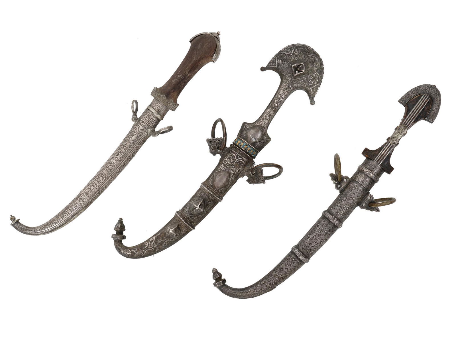 A LOT OF THREE MOROCCAN KOUMYA DAGGERS, 19-20TH CC.: The lot consists of three Moroccan daggers "koumya" of the late 19th - early 20th century. All three daggers have characteristic curved steel blades. The grips are made of carved horn, silver and bras