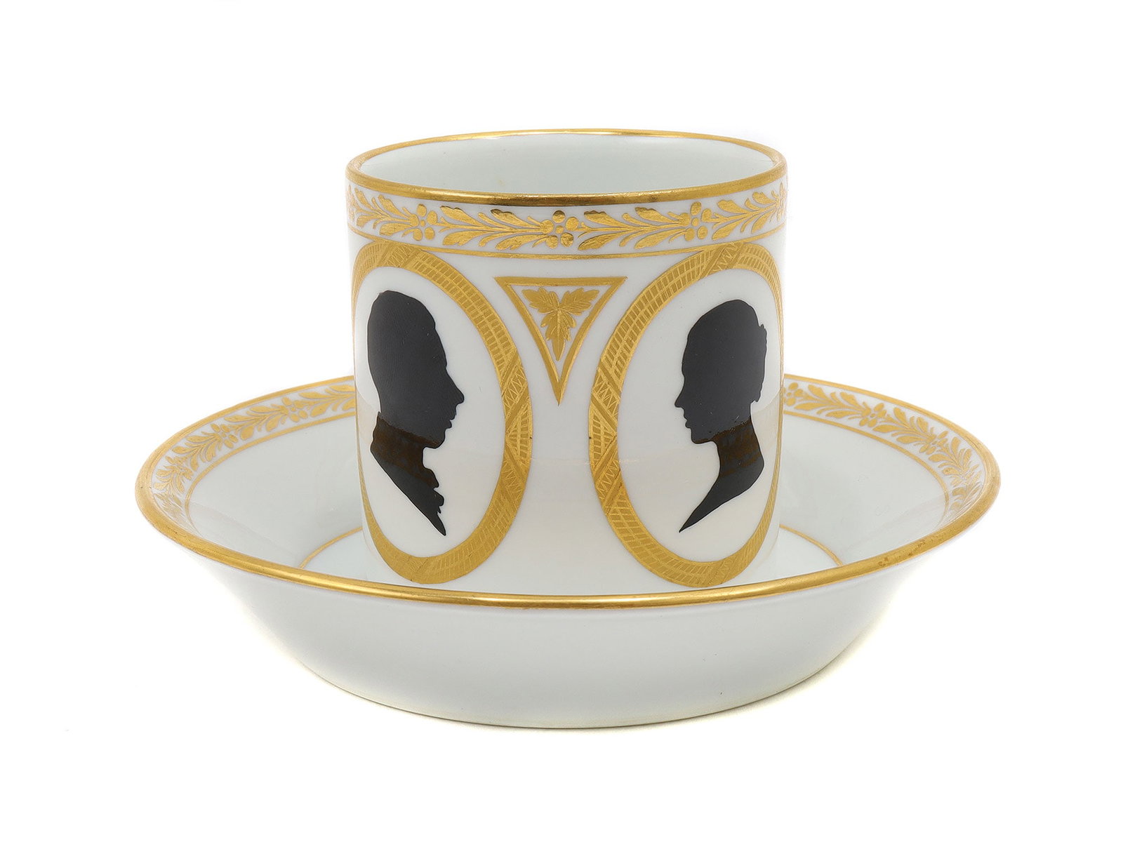 A MEISSEN PORCELAIN PRESENTATION CUP AND SAUCER, C.1872: An antique 19th-century Meissen porcelain cup and saucer decorated with gilt trim and silhouette medallions of Alfred Graf Schlieffen and Anna Schlieffen. The cup features a crossed swords mark in blu