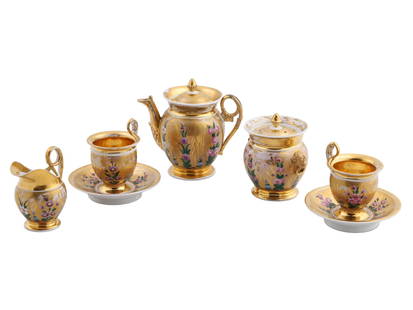 AN EARLY RUSSIAN PORCELAIN TEA SET BY GARDNER, 19TH CEN.: The set comprises a sugar bowl, a pair of tea cups with saucers, a creamer and a teapot, each piece is heavily gilded with polychrome floral decoration. The sugar bowl handles are modeled in the shape